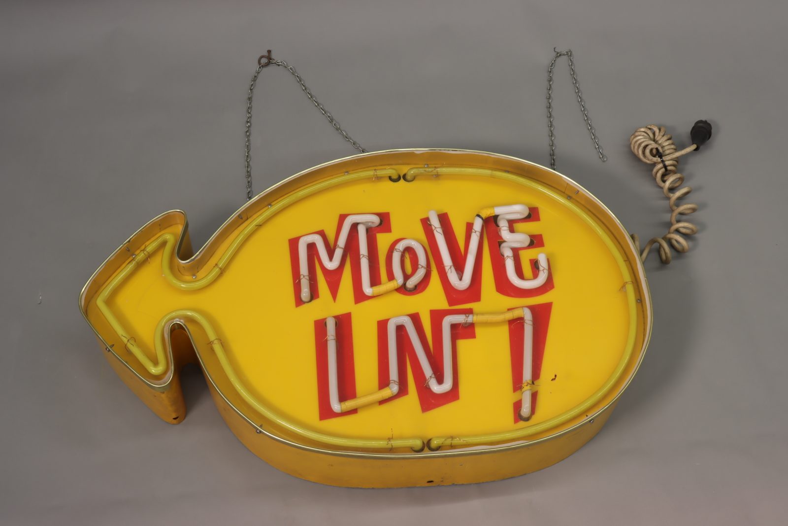 Vanha, keltainen neonvalokyltti, jossa teksti Move in!